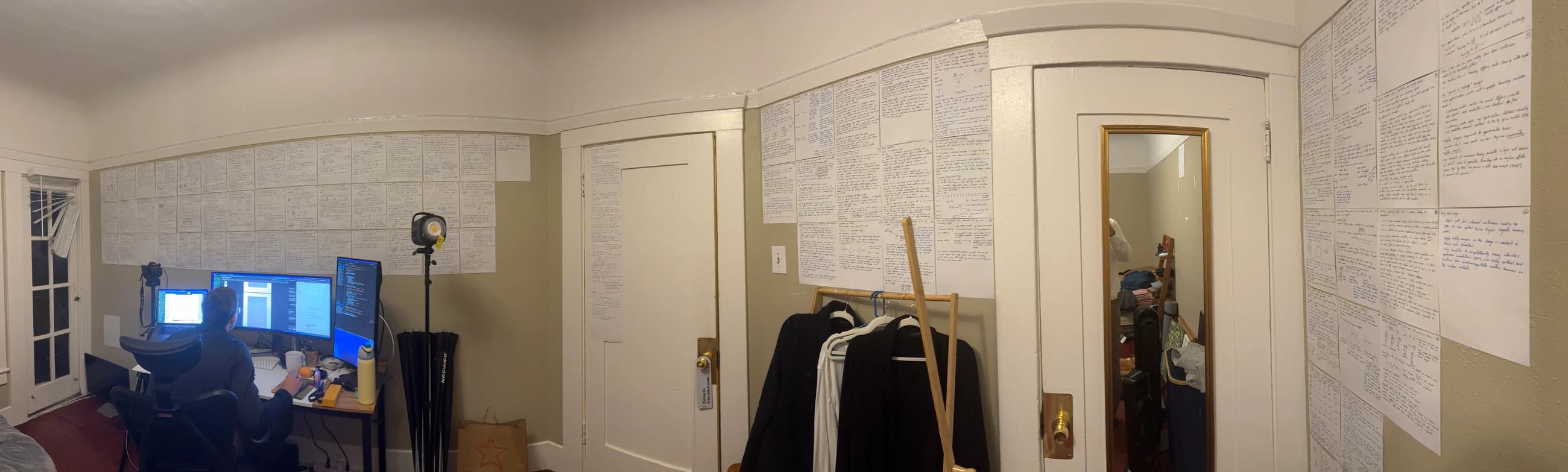 Working at my desk, surrounded by handwritten research notes covering the walls.
